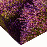 Close-up of a stretched canvas artwork depicting a serene countryside landscape with vibrant green fields, rolling hills, and a clear blue sky, perfect for home decor.