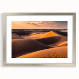Framed wall art featuring a serene desert landscape with golden dunes, encased in a stylish silver frame and white matting, ideal for home decor.