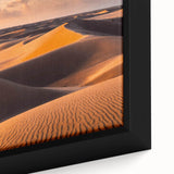 Framed canvas wall art showcasing a close-up of undulating sand dunes, featuring warm beige and golden hues that evoke a serene desert landscape atmosphere.