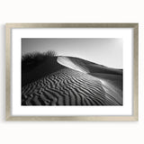 Framed wall art featuring a serene desert landscape with rolling dunes, presented in a sleek silver frame with a white mat, ideal for modern home decor.
