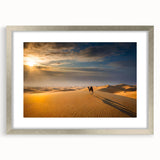 Framed wall art featuring a serene landscape of golden sand dunes under a soft blue sky, elegantly displayed with a silver mat and frame, perfect for modern home decor.