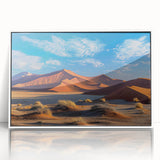 Framed wall art showcasing a serene desert landscape with soft, rolling sand dunes under a vibrant sunset. The acrylic frame features a sleek white border, enhancing the artwork's natural beauty and modern appeal, perfect for home decor.