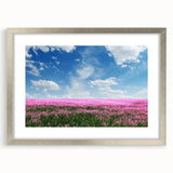 Framed wall art depicting serene landscapes with lush green fields and blue skies, elegantly set in a silver frame with a white mat, ideal for home decor.
