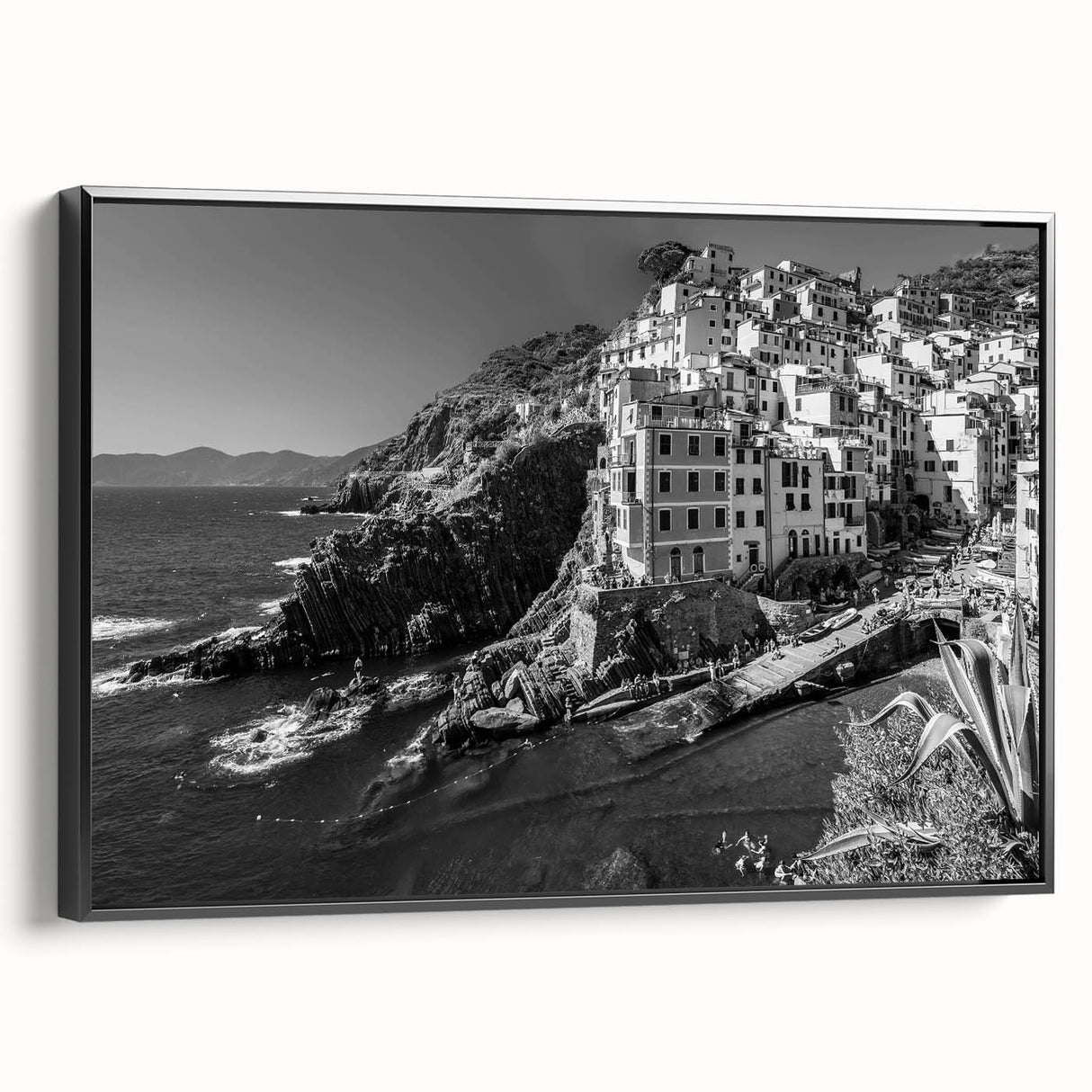 Framed canvas wall art showcasing a serene harbor landscape design, featuring vibrant blues and greens. The artwork is displayed in a sleek black frame, enhancing its visual appeal. Perfect for adding a touch of tranquility to modern home decor.