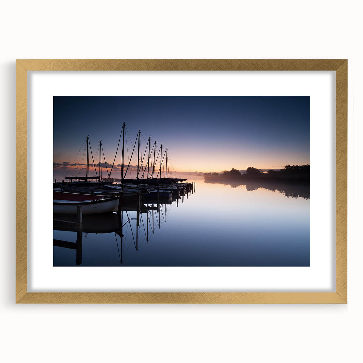 Framed wall art featuring a serene harbor landscape with a gold mat, ideal for enhancing home decor. The piece showcases calming blue tones and intricate details, perfect for nautical-themed interiors.