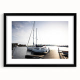 Framed wall art featuring a serene harbor landscape with soft blue and green hues, showcased in a sleek black frame with a mat, perfect for home decor.