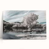 Stretched canvas wall art depicting a serene lake landscape with vibrant colors, elegantly leaning against a neutral-colored wall, perfect for home decor.