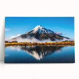 Stretched canvas wall art depicting a serene lake landscape with vibrant colors, leaning against a rustic wall, perfect for enhancing home decor aesthetics.