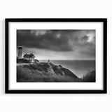 Framed wall art featuring a serene lighthouse landscape design in a black frame with a white mat, ideal for coastal-themed home decor. This elegant piece enhances interior spaces with its calming blue and green hues, perfect for living rooms or offices.