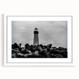 Framed wall art featuring a coastal lighthouse design, mounted with a white mat, showcasing tranquil ocean waves and a bright blue sky, perfect for enhancing home decor.