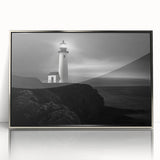 Framed wall art featuring a picturesque lighthouse design in vibrant colors, set against a serene landscape, perfect for coastal-themed decor. The sleek silver frame enhances the artwork's modern aesthetic, ideal for living rooms or offices.