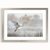 Framed wall art featuring a serene marsh landscape with lush greenery and soft blue water, accented by a silver frame and white matting, perfect for home decor.