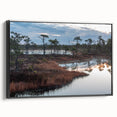 Framed canvas wall art showcasing a serene marsh landscape with lush greenery and a tranquil swamp scene, highlighted by rich earthy tones and a sleek black frame.