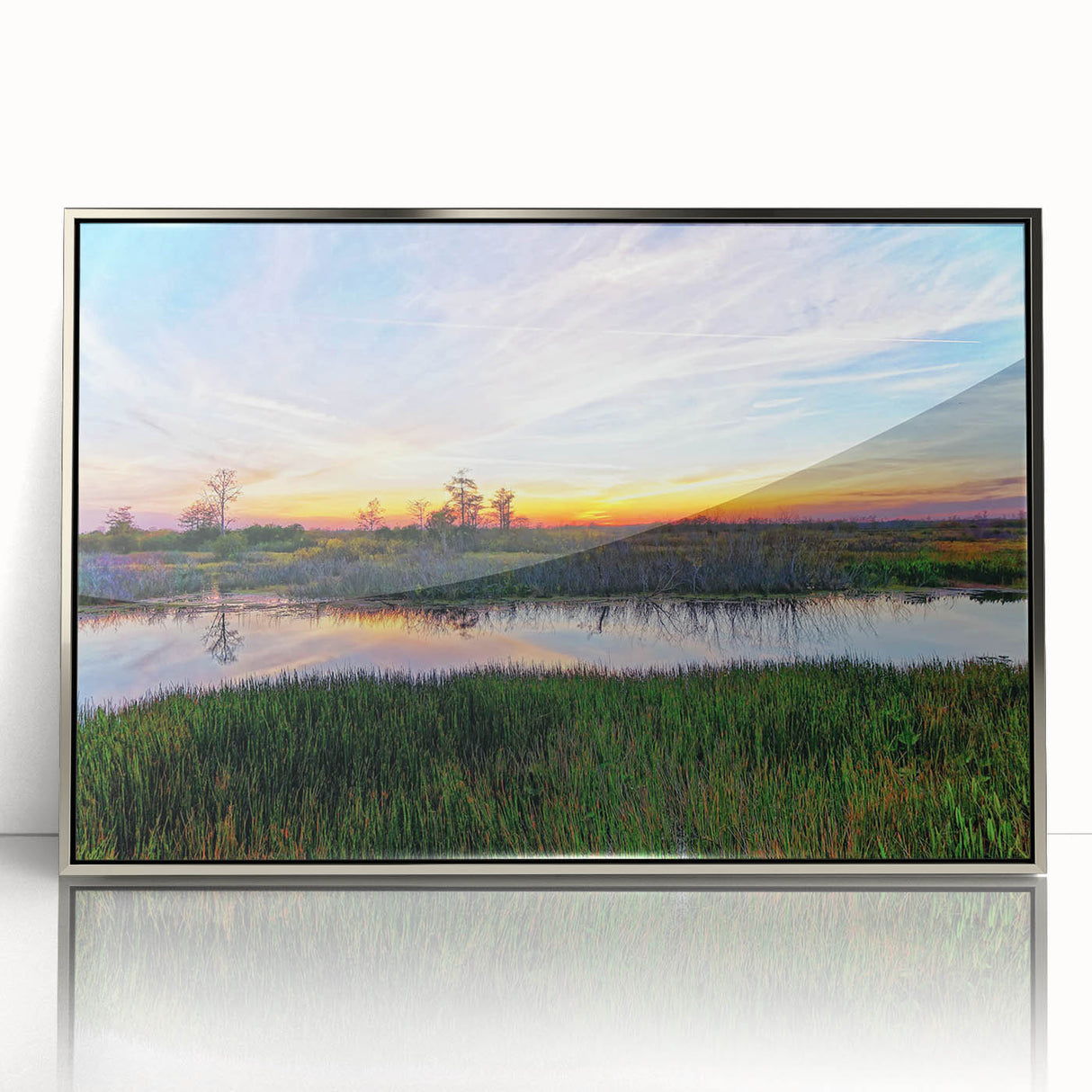 Framed wall art featuring a vibrant marsh landscape design with lush greenery and reflective water, set in a sleek silver frame, perfect for enhancing home decor.