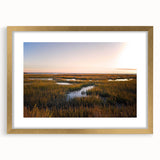 Framed wall art featuring a serene marsh landscape with lush greenery and tranquil water, accented by a gold frame and mat, perfect for home decor.