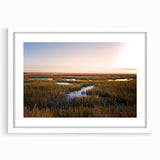 Framed wall art depicting a serene marsh landscape with greenery and water, featuring a white mat for an elegant presentation. Perfect for nature-themed decor.
