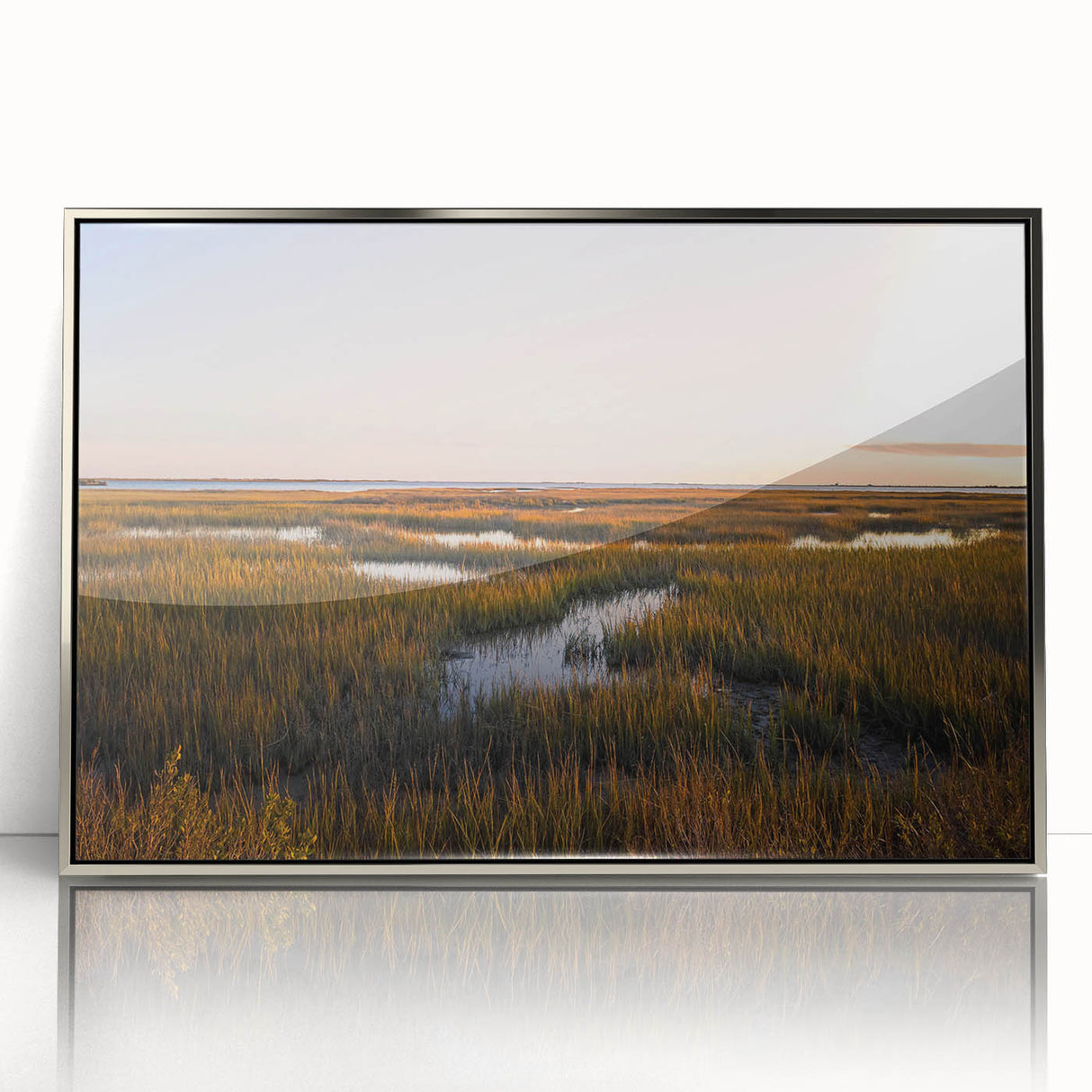 Framed wall art showcasing a serene marsh landscape design with lush greenery and tranquil water reflections, presented in a sleek silver frame for an elegant finish. This piece enhances any nature-themed decor, blending artistic beauty with natural tranquility.