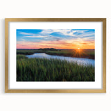 Framed wall art featuring a serene marsh landscape with lush greenery and soft water reflections, enhanced by a gold mat. Perfect for nature-inspired decor.