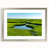 Framed wall art featuring a serene marsh landscape with lush greenery and calm water, elegantly presented in a silver frame with a mat for an upscale decor look. This artwork adds a tranquil touch to any interior space, perfect for nature lovers.