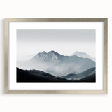 Framed wall art featuring a serene misty landscape in soft gray tones, accented by a silver frame and mat, ideal for modern home decor aesthetics.