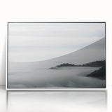 Framed wall art depicting a serene landscape shrouded in mist, featuring soft gray and white tones with a sleek white frame, perfect for home decor.