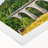 Vibrant rolled canvas wall art depicting a serene railroad landscape with lush greenery and a clear blue sky, perfect for home decor and art enthusiasts.