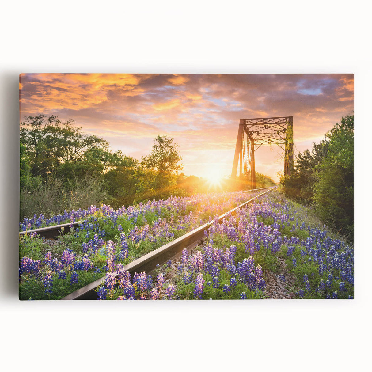 Stretched canvas wall art featuring a vibrant landscape scene of a railroad traversing lush green hills under a bright blue sky, perfect for home decor.