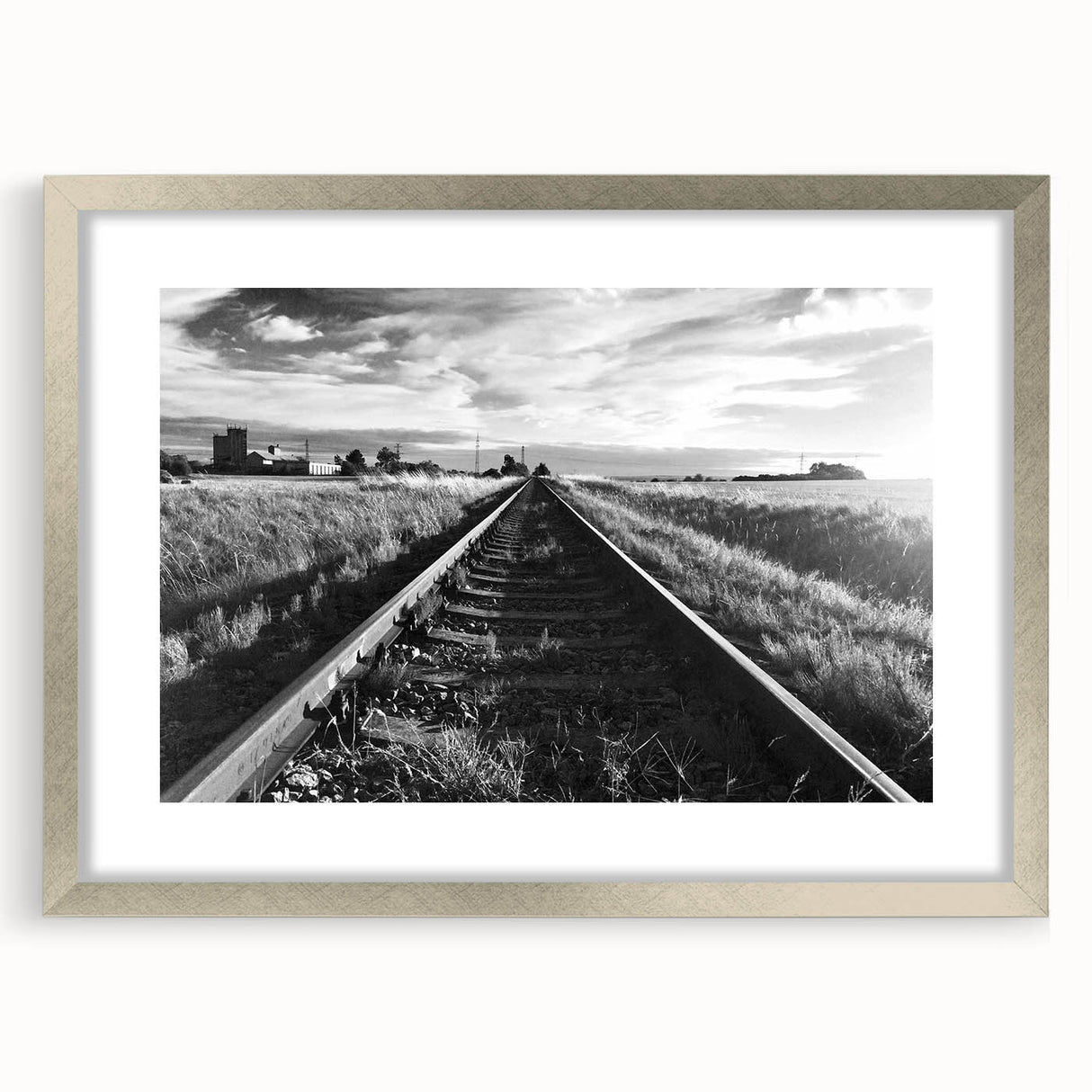 Framed wall art featuring a serene landscape with railroad tracks, silver matting, and a sleek frame, perfect for enhancing modern home decor.
