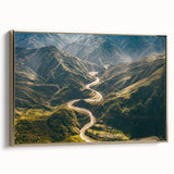 Framed canvas wall art showcasing a serene landscape with winding roads and lush greenery, highlighted by a gold frame and soft sunlight enhancing the colors.