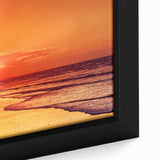 Framed canvas wall art showcasing a serene seascape with vibrant blue ocean waves and a golden sunset, perfect for home decor. The design emphasizes tranquil nature themes and adds a calming touch to interiors.