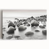 Stretched canvas artwork depicting a serene seascape with vibrant blues and soft whites, showcasing waves crashing on a rocky shore, perfect for coastal decor.