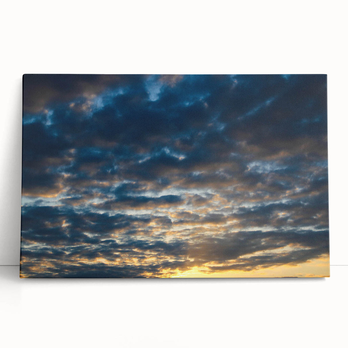 Stretched canvas wall art showcasing a vibrant landscape with sunset hues, elegantly leaning against a neutral wall, perfect for modern home decor.