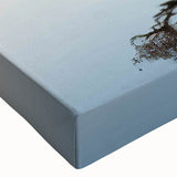 Close-up of a vibrant, stretched canvas wall art piece showcasing a serene landscape with lush green trees and a clear blue sky, ideal for home decor.