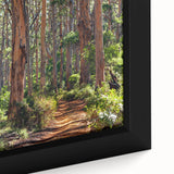 Close-up of a framed canvas wall art piece showcasing a serene landscape with lush green trees, vibrant foliage, and a calming blue sky, perfect for home decor.