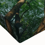 Close-up of a stretched canvas artwork depicting a serene landscape with lush green trees and a vibrant blue sky, perfect for enhancing home decor.