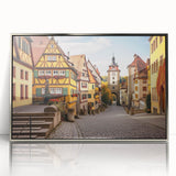 Framed wall art showcasing a serene landscape of a picturesque village, featuring vibrant colors and intricate details in a sleek silver frame, perfect for home decor.