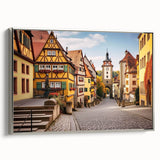 Framed wall art showcasing a serene village landscape with vibrant colors, displayed in a sleek silver frame, perfect for enhancing home décor.