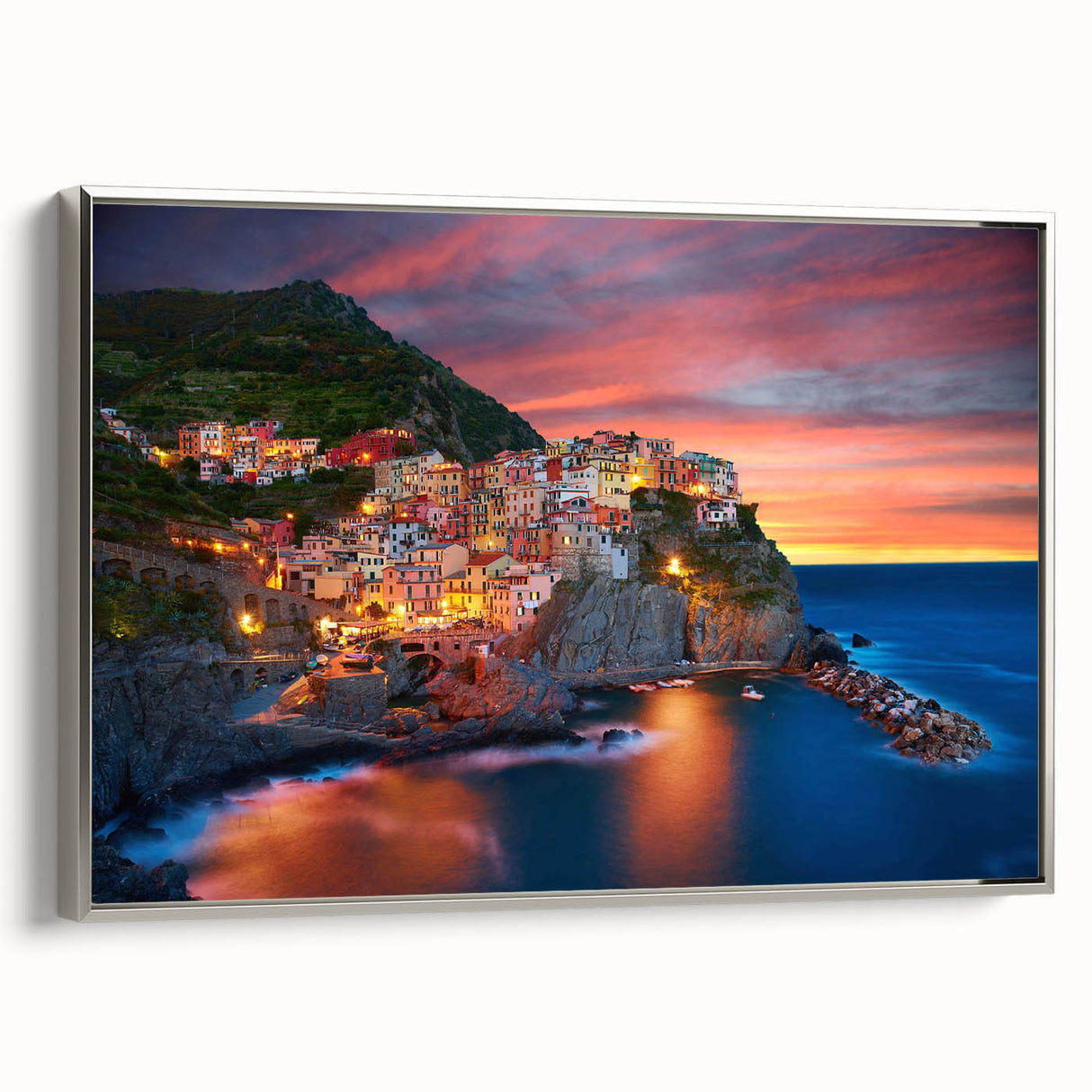 Framed canvas wall art showcasing a serene village landscape design with vibrant colors and intricate details, set in a sleek silver frame for an elegant display.