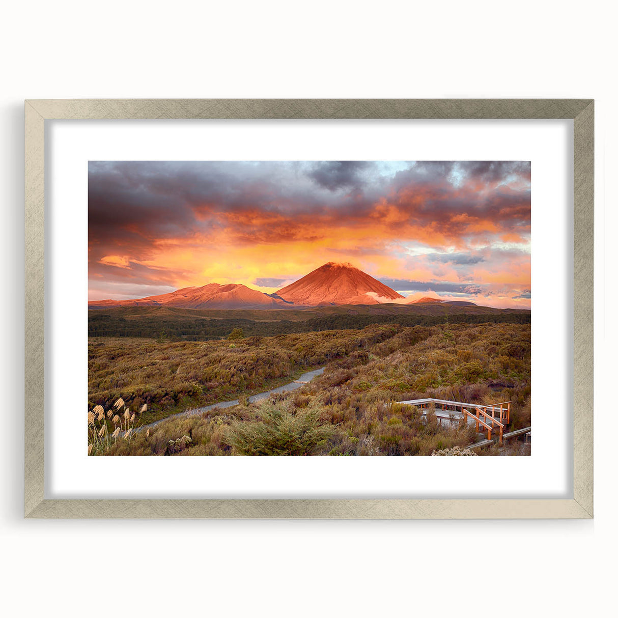 Framed landscape wall art featuring a vibrant volcano design in rich colors, set in a sleek silver frame with a white mat, ideal for home decor.