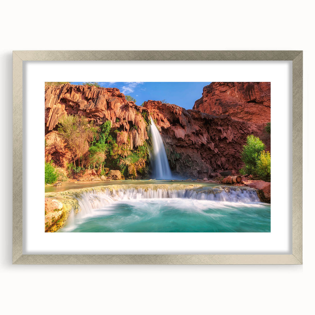 Framed silver wall art featuring a serene waterfall landscape, complete with a white mat, showcasing vibrant blues and greens for a tranquil home decor accent.