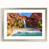 Framed silver wall art featuring a serene waterfall landscape, complete with a white mat, showcasing vibrant blues and greens for a tranquil home decor accent.