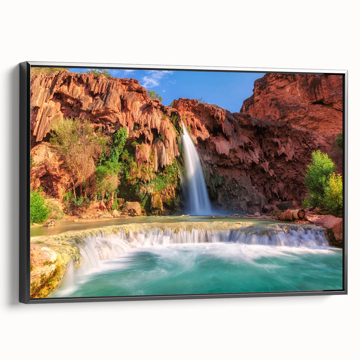 Framed canvas wall art showcasing a stunning waterfall landscape, featuring vibrant blues and greens. The artwork is displayed with a sleek black frame, enhancing its visual appeal for home decor. Perfect for nature enthusiasts seeking to elevate their living space.
