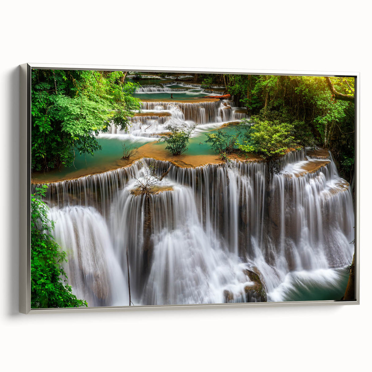 Framed canvas wall art depicting a serene waterfall landscape, featuring vibrant blues and greens, elegantly showcased with a silver frame for a modern touch.