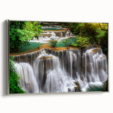 Framed canvas wall art depicting a serene waterfall landscape, featuring vibrant blues and greens, elegantly showcased with a silver frame for a modern touch.