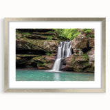 Framed wall art showcasing a serene landscape with a cascading waterfall, elegantly presented in a silver frame with a mat, perfect for home decor.