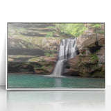 Framed wall art piece showcasing a stunning waterfall landscape in vibrant blues and greens, featuring a sleek white frame, ideal for home decor.