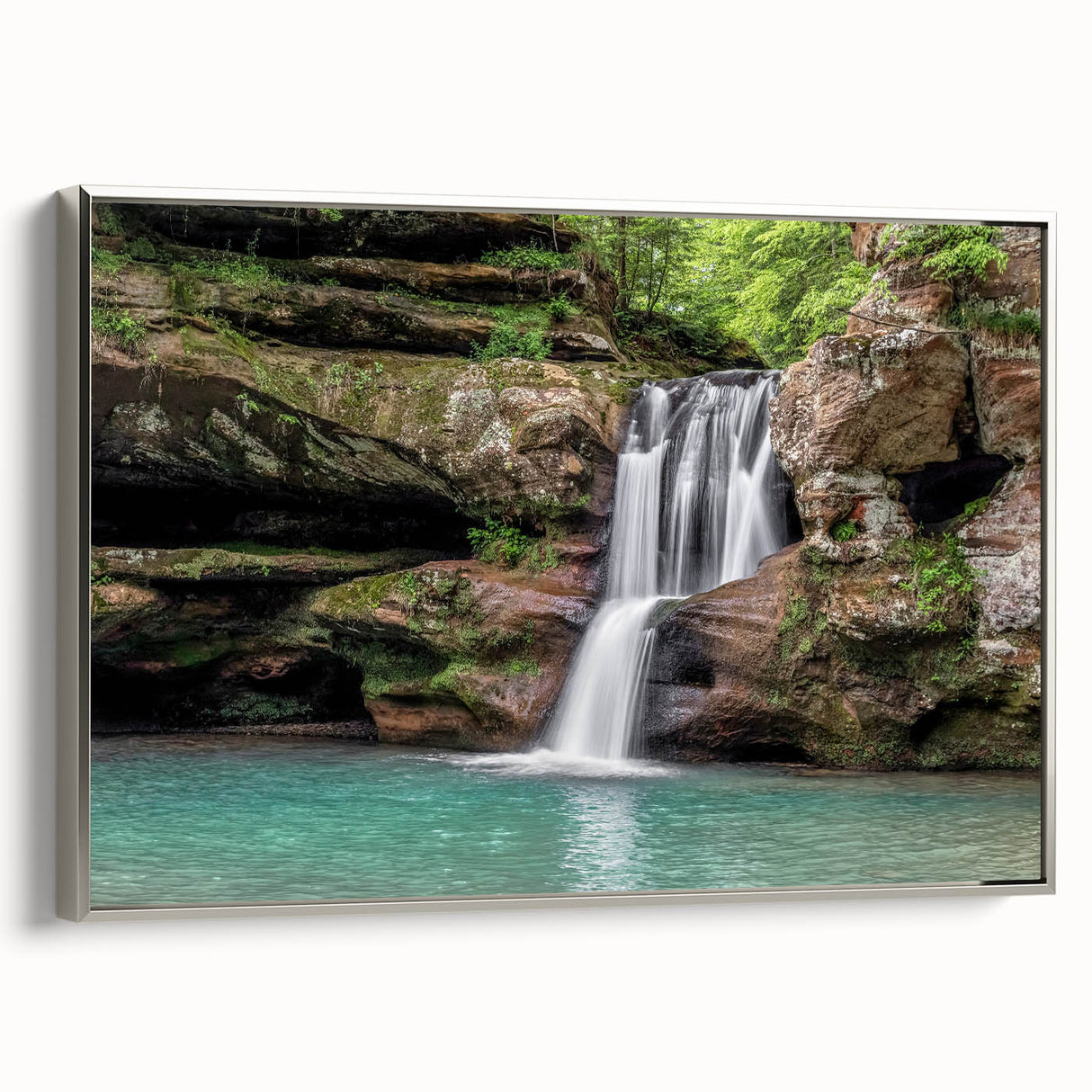 Framed canvas wall art showcasing a serene waterfall landscape, highlighting vibrant blues and greens, with a sleek silver frame, ideal for home decor.