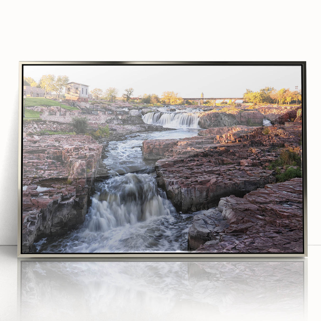 Framed acrylic wall art featuring a serene waterfall in a lush landscape, accented by a silver frame, perfect for enhancing home decor with nature's beauty.