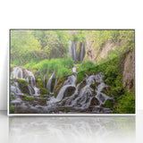 Framed acrylic wall art featuring a serene landscape with a cascading waterfall, surrounded by lush greenery. The design enhances any modern home decor aesthetic.