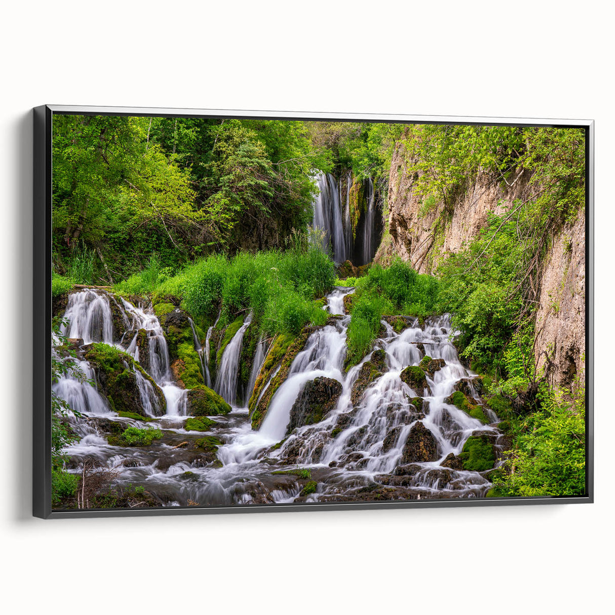 Framed canvas wall art showcasing a serene waterfall landscape with lush greenery, presented in a sleek black frame, ideal for home decor enhancement.